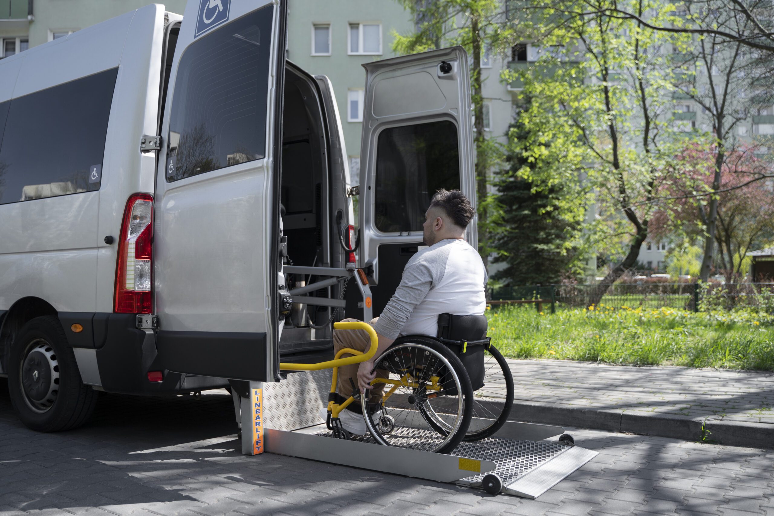 Patient in wheelchair using the ramp to enter a wheelchair-accessible medical transport van